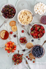Summer berries strawberries, blueberries, sweet cherries in vases on the table. Top view