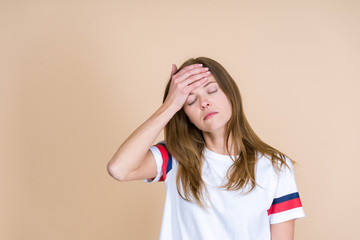 Front view of tired adult girl with closed eyes touching forehead