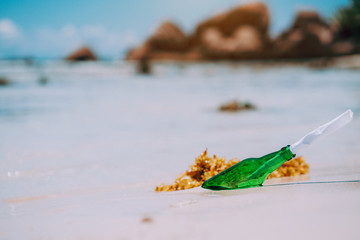 Bottle with message on white paradise sandy beach with blurred background. conceptual photo