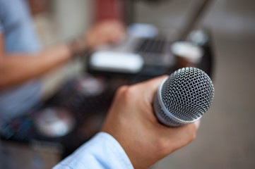 A microphone in the hand at a live outdoor party.