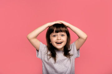 Portrait of funky cute astonished surprised child kid little girl touch hand head shout yell wonder hear incredible information bargain impressed dressed grey clothing isolated pink background