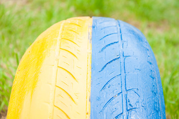 part of an automobile rubber tire. Painted in yellow and blue. As a fence