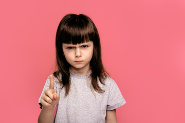 Annoyed little girl with bad attitude making stop gesture with her palm outward, saying no,...