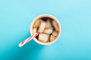 Refreshing iced coffee in a glass on a blue background. Concept summer, cola with ice, refreshing cocktail, thirst. Flat lay, top view