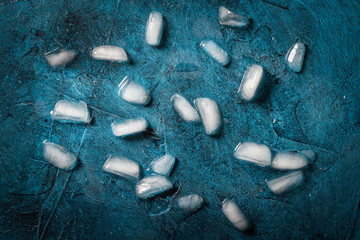 Ice cubes on a dark blue stone background. Flat lay, top view