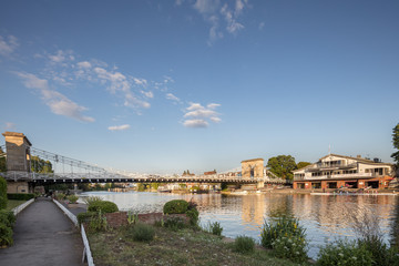 Fototapeta premium Marlow suspension bridge and the Marlow rowing club on the river Thames in Buckinhamshire, UK on a warm summer's evening