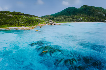 Tropical coastline of La Digue island with granite boulders and paradise beaches, view from the sea, Seychelles