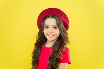 Little girl with long hair. Kid happy cute face adorable curly hair yellow background. Lucky and beautiful. Beauty tips for tidy hair. Smiling child. Kid girl long healthy shiny hair wear red hat