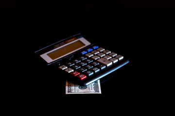 Expenses cost, budget and tax or investment calculation, one hundred dollar with calculator on dark black background table with blank copy space.
