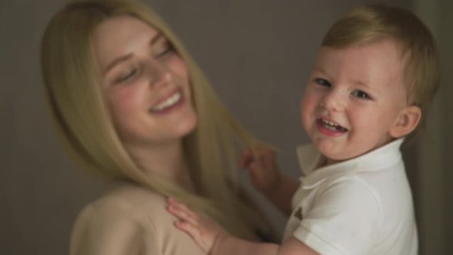 Beautiful young blonde mom playing with her baby boy son - Family values goal - Caucasian mother and child at home - Smooth cinematic handheld movement