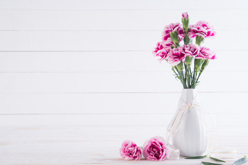 Valentines day and love concept. Pink carnation flower in vase on white wooden background.