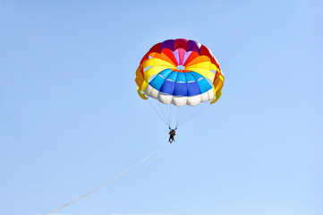 Para sailing using a parachute on background of blue sky.