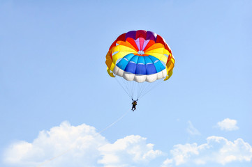 Para sailing using a parachute on background of blue cloudy sky.