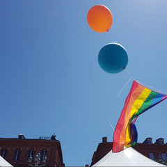 Rainbow flags and balloonson sky background and and brick building