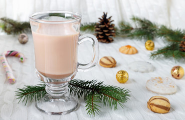 Glass cup of hot cocoa with milk,  candies and  straw tube on background