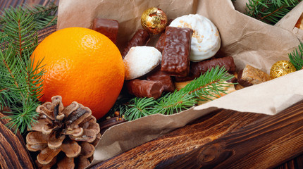 Fototapeta na wymiar Delicious sweets, chocolates, cookies and oranges for gifts in wooden box on vintage table