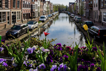 Fototapeta na wymiar Gouda, Holland, Netherlands, April 23, 2019, bicycles parked near a bridge in a street in Gouda old town. Flowers (tulips) on the foreground in a flowerbed