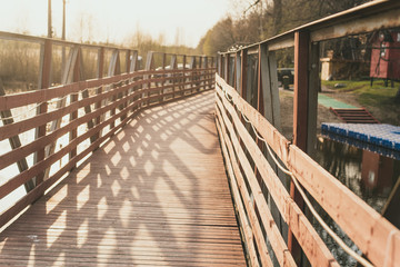 wooden bridge on the river. sunset sun on the background.