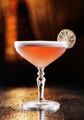 Cold cocktail with pink champagne in tall glass on backdrop of the restaurant atmosphere. Summer drinks and cocktails