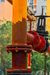 Rusty natural gas pipeline painted in peeling yellow with Valve and bolts and nuts