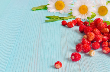 Ripe strawberries with plant leaves on blue wooden background, strawberries in white old mug, healthy food concept