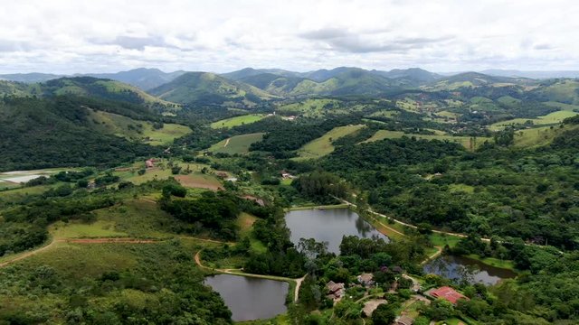 Aerial landscape view of green valley in tropical country with forest, lake & surrounded by luxury wealthy villa. Monte Alegre Do Sul. Brazil. Tropical countryside destination for local tourist.