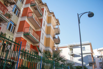 Closeup of part of residential buildings with multi-colored balconies against a blue sky