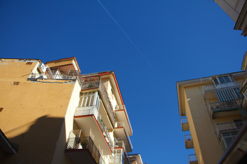 Closeup of part of residential buildings with multi-colored balconies against a blue sky