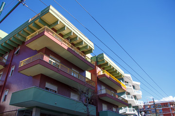 Closeup of part of residential buildings with multi-colored balconies against a blue sky