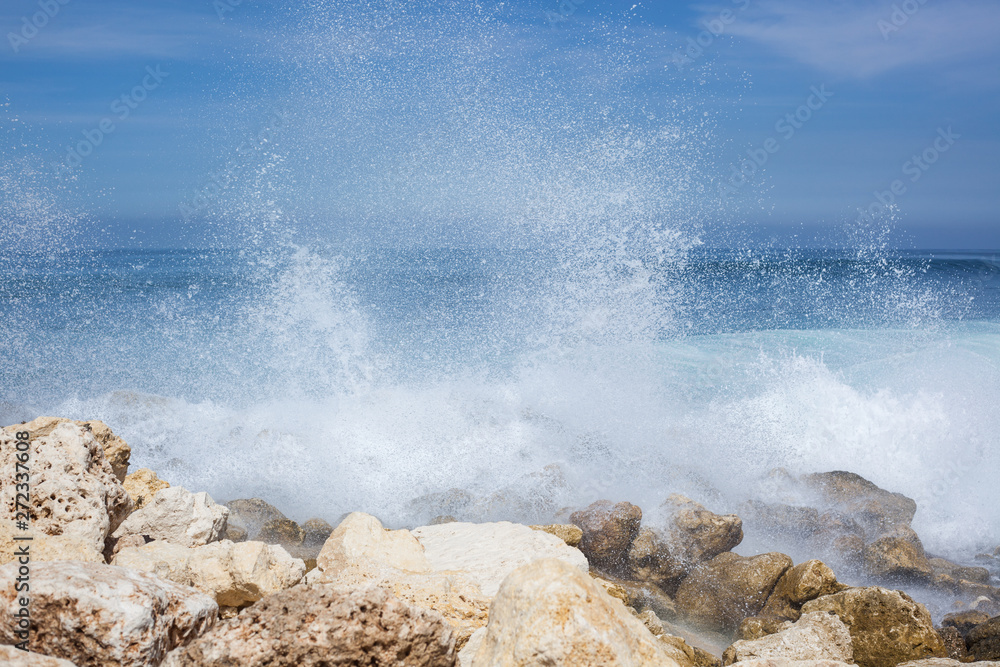 Wall mural sea view. blue ocean, big waves, black and white stones, high tide, water splash