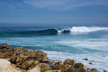 sea view. blue ocean, big waves, black and white stones, high tide