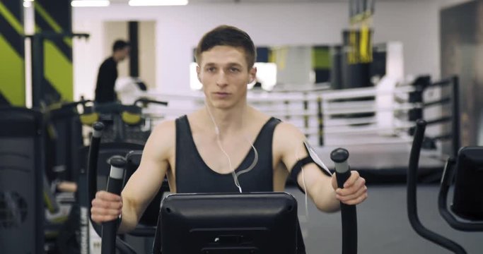 Jogger guy wearing t-shirt listening music while practices orbitrek