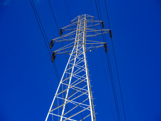 high voltage metal construction tower line front of the clear blue sky