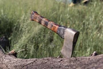Tourist or camping old vintage hatchet stuck in a wooden log after chopping, tourist or hiking or survival or lumberjack tool