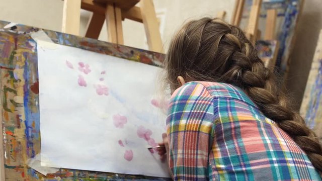 Little Girl artist draws at the easel. Drawing process: close-up of brush and canvas.
