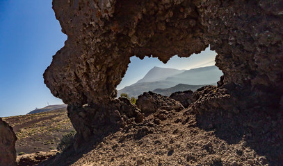 Mountains and lava fields around volcano Teide, partly covered by the clouds. Bright blue sky. Teide National Park, Tenerife, Canary Islands, Spain