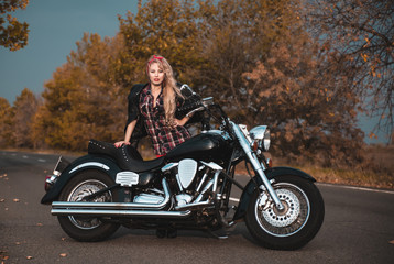 Beautiful biker woman posing with motorcycle on the road.