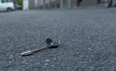 The lost bunch of keys, lies on the asphalted sidewalk of the road, near the entrance of an apartment building in the city