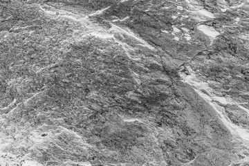 Vintage monochrome background. Rough painted wall of black and white color. Imperfect plane of grayscale. Uneven old decorative backdrop. Texture of black-white. Monochromatic ornamental stony surface
