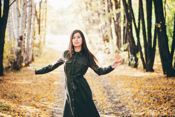 Dreamy dancing girl with long natural black hair on autumn background with trees and yellow leaves...