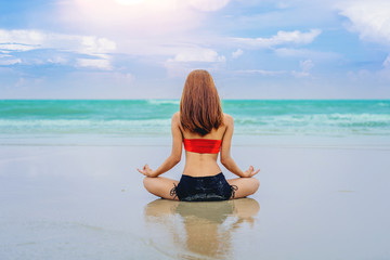 Fototapeta na wymiar Young woman doing practice yoga on the sea beach at sunset