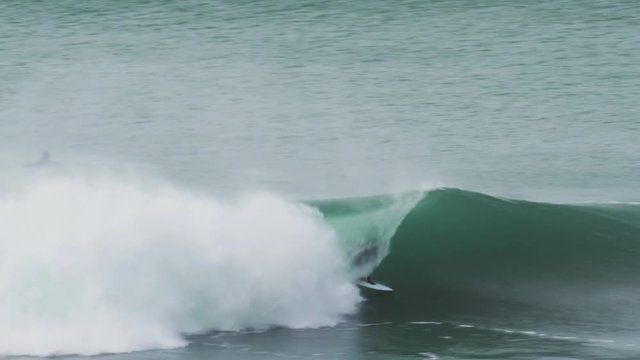Surfer in Cornwall in Porthleven scores a small barrelling wave in clean offshore conditions in the beautiful blue water