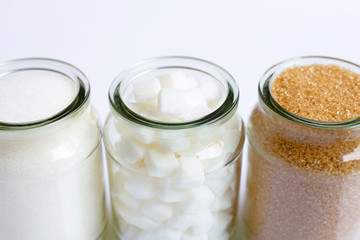 Various types of sugar in a glass jar on white