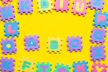 Alphabet puzzle on yellow background.