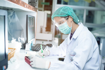 Portrait of a female researcher working in a lab scientist using microscope with colleague working in background