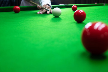 Playing snooker, piercing the red ball, black, aiming the ball and pocketing the hole to score points.