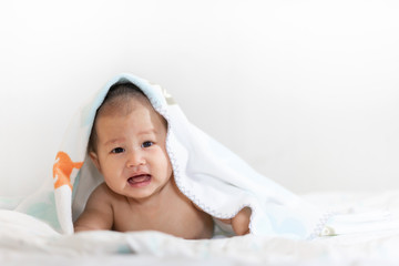Fototapeta na wymiar Portrait of happy smile baby relaxing under towel after bath on the bed