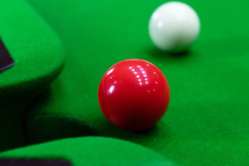 Playing snooker, piercing the red ball, black, aiming the ball and pocketing the hole to score points.