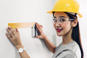 Young woman construction engineer in a yellow helmet working and  looking job for planning project at building home site