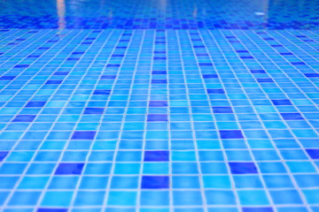 Obraz premium swimming pool ceramic tiles covered in clear water. light blue tiles dotted with deep blue tiles in a regular pattern design. recreation pool design.